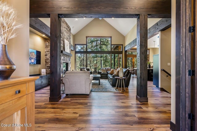 living room with a fireplace, dark hardwood / wood-style floors, beamed ceiling, and high vaulted ceiling