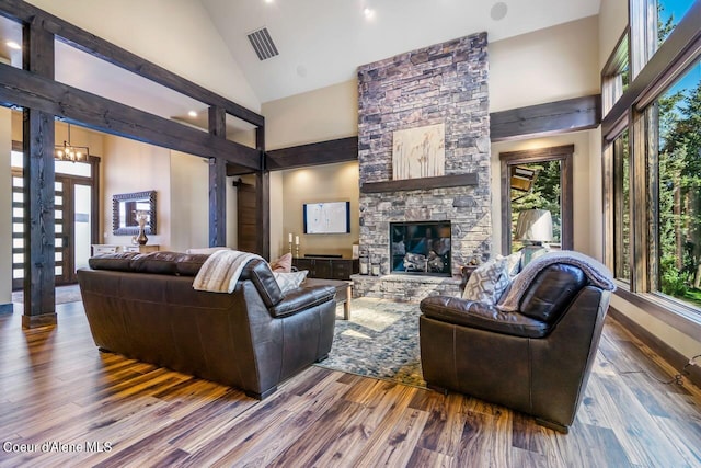 living room with high vaulted ceiling, hardwood / wood-style floors, and a stone fireplace