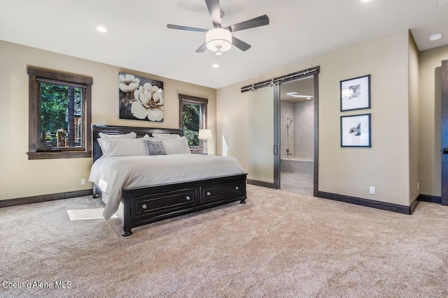 carpeted bedroom featuring a barn door, ensuite bath, and ceiling fan