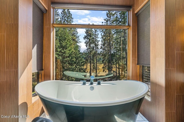 bathroom featuring tile walls, tile patterned flooring, and a washtub