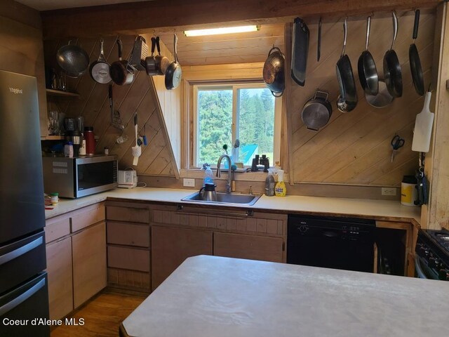 kitchen with light hardwood / wood-style flooring, black appliances, sink, and wooden walls