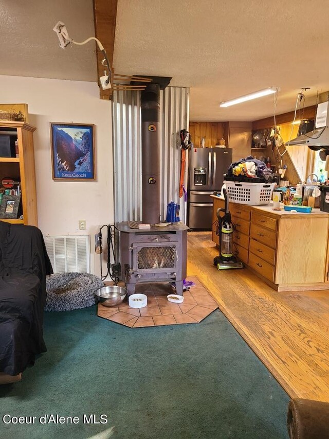 carpeted living room with a textured ceiling, a wood stove, and wood walls