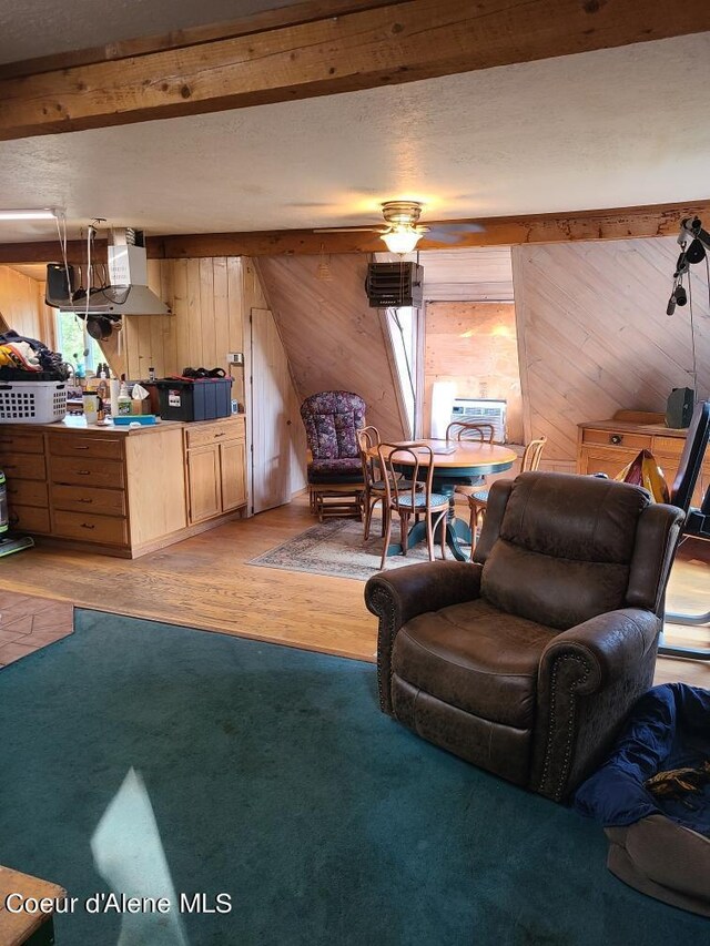 living room with light hardwood / wood-style floors, wood walls, and ceiling fan