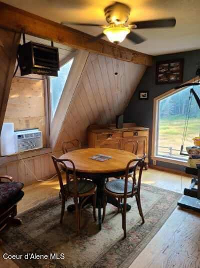 dining space featuring wood walls, vaulted ceiling with beams, cooling unit, hardwood / wood-style floors, and ceiling fan