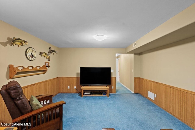 living room featuring wooden walls and light colored carpet