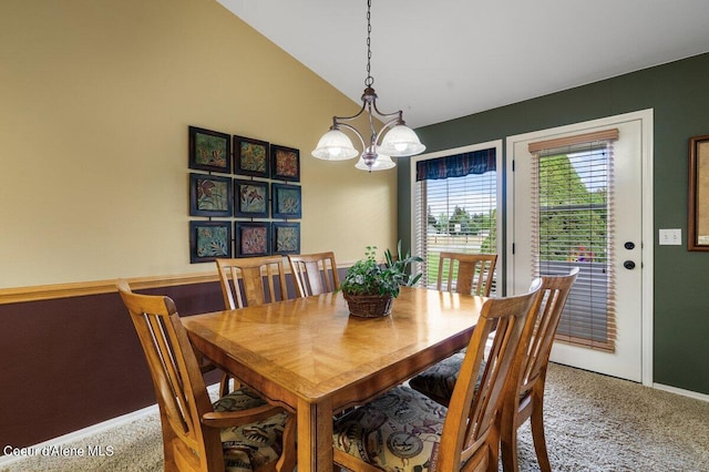 carpeted dining area featuring lofted ceiling and a chandelier