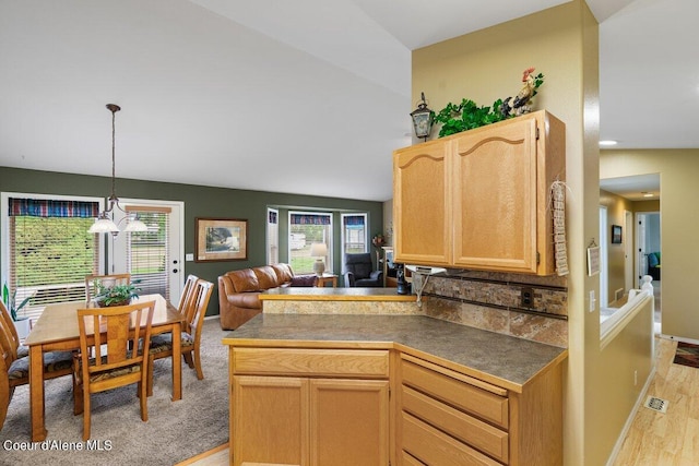 kitchen featuring light wood-type flooring, a chandelier, vaulted ceiling, light brown cabinets, and decorative light fixtures