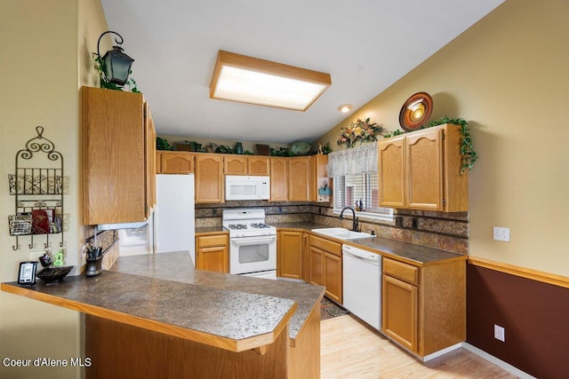 kitchen with vaulted ceiling, sink, kitchen peninsula, and white appliances