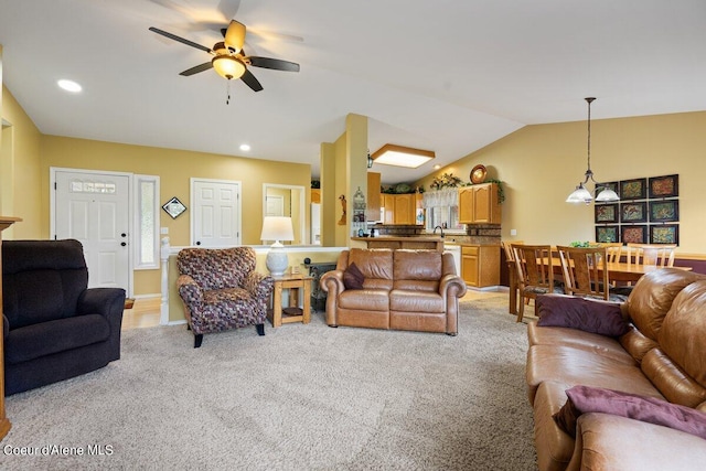 living room featuring ceiling fan, light colored carpet, sink, and vaulted ceiling