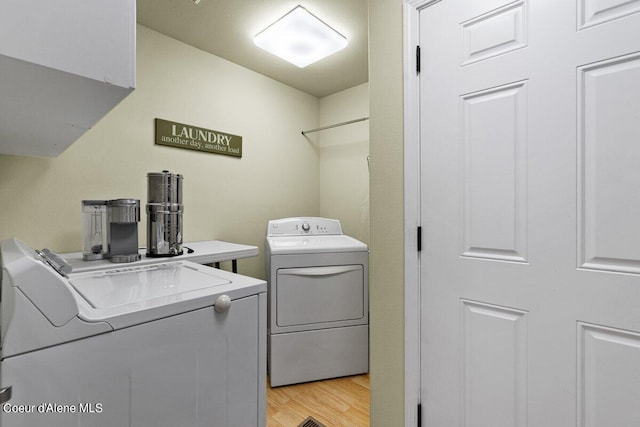 clothes washing area with light hardwood / wood-style flooring and washer and dryer