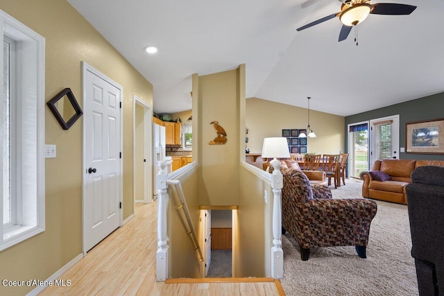 living room featuring light hardwood / wood-style flooring, vaulted ceiling, and ceiling fan