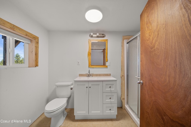 bathroom featuring tile patterned flooring, toilet, a shower with door, and vanity