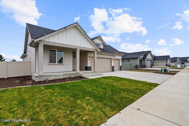 view of front of property featuring covered porch, a garage, and a front yard