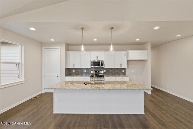 kitchen with a center island with sink, decorative light fixtures, stainless steel appliances, and dark wood-type flooring