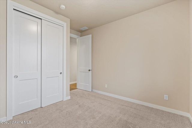 unfurnished bedroom with a closet and light colored carpet