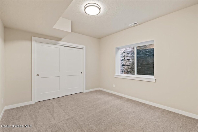 unfurnished bedroom with a textured ceiling, light carpet, and a closet