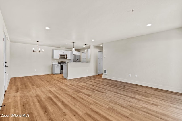 unfurnished living room featuring visible vents, baseboards, recessed lighting, light wood-style flooring, and a notable chandelier