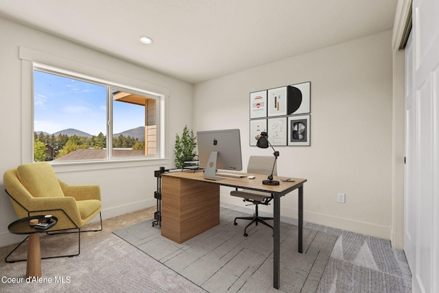 office area featuring baseboards and light carpet