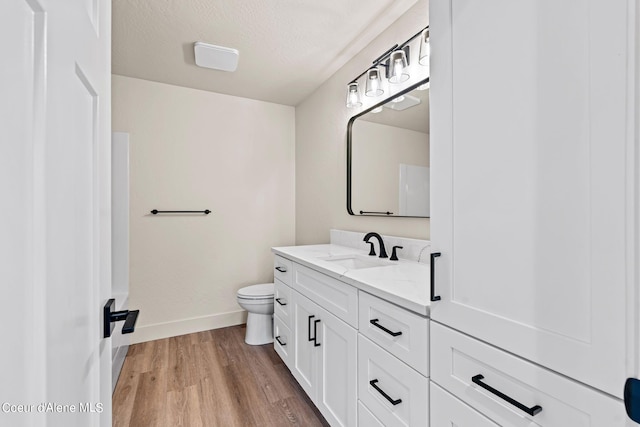 bathroom featuring vanity, wood finished floors, baseboards, a textured ceiling, and toilet