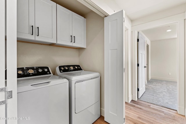 washroom featuring baseboards, cabinet space, light wood-style floors, and independent washer and dryer