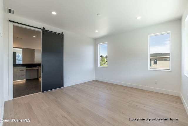 spare room with light hardwood / wood-style flooring and a barn door