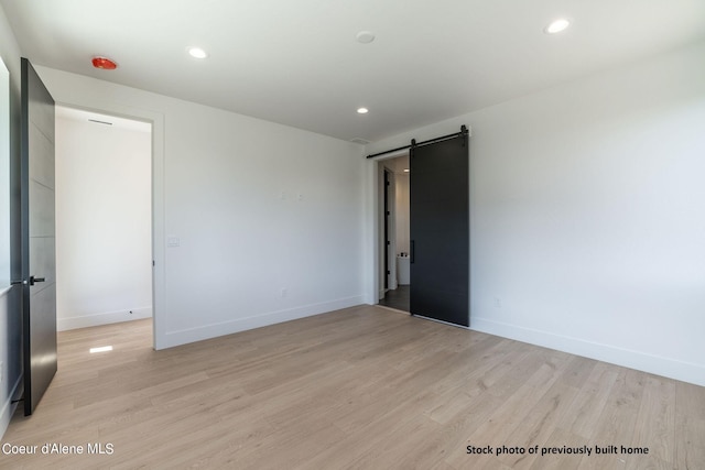 spare room featuring a barn door and light wood-type flooring