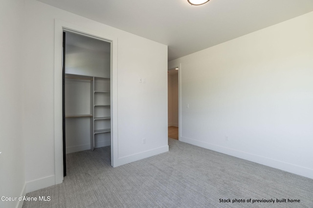 unfurnished bedroom with light carpet, a closet, and a walk in closet