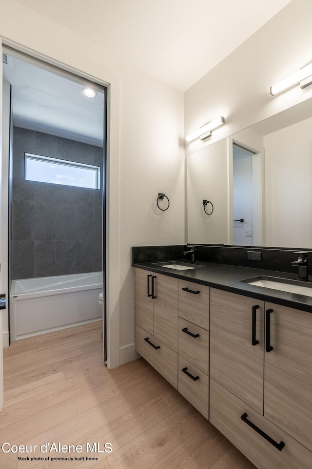 full bathroom with tiled shower / bath, vanity, toilet, and hardwood / wood-style flooring