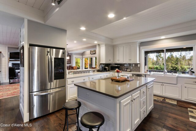 kitchen with white cabinets, appliances with stainless steel finishes, plenty of natural light, and dark hardwood / wood-style flooring