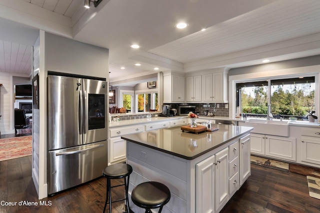 kitchen with stainless steel appliances, tasteful backsplash, a center island, and dark wood finished floors