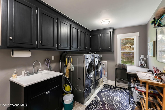washroom featuring baseboards, a sink, cabinet space, and washer and clothes dryer