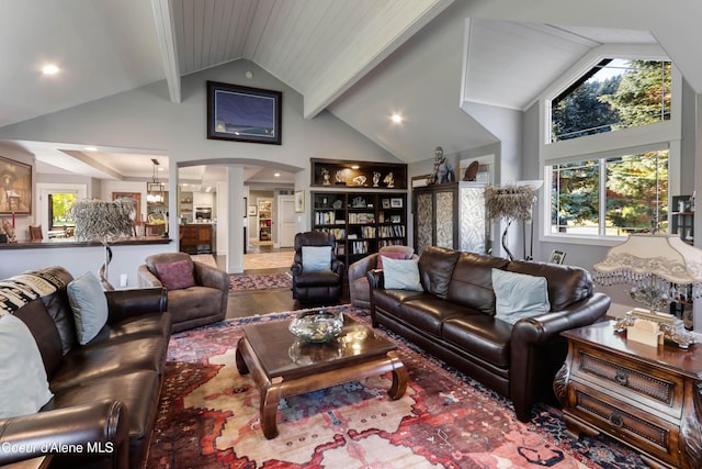 living area with arched walkways, beamed ceiling, ornate columns, wood finished floors, and high vaulted ceiling