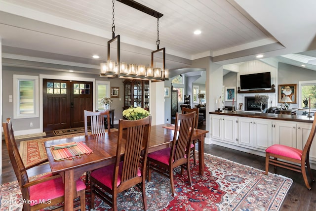 dining area with dark wood-style flooring, a fireplace, recessed lighting, lofted ceiling, and arched walkways