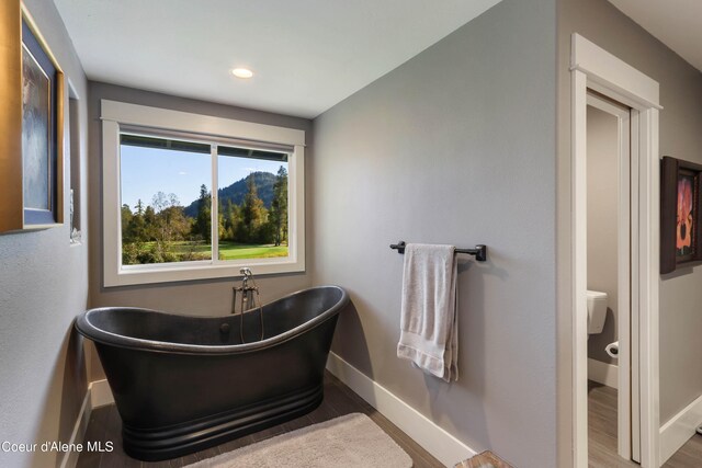 bathroom with wood-type flooring, toilet, and a tub