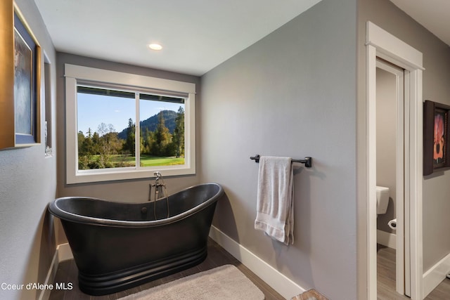bathroom featuring recessed lighting, a freestanding tub, baseboards, and wood finished floors
