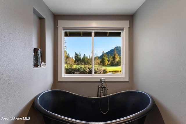 bathroom with a freestanding bath and a textured wall
