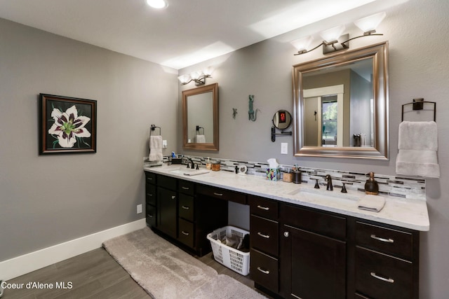 full bathroom featuring wood finished floors, double vanity, a sink, and backsplash