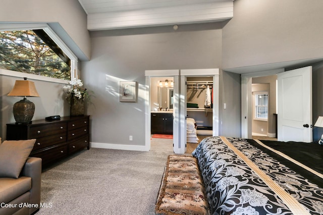 bedroom featuring a closet, baseboards, ensuite bath, carpet floors, and a walk in closet