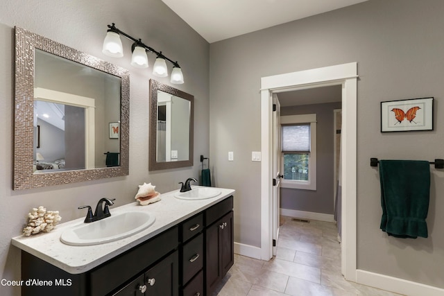 full bathroom with tile patterned floors, double vanity, a sink, and baseboards
