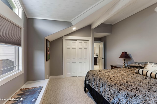 bedroom with carpet floors, baseboards, a closet, and lofted ceiling