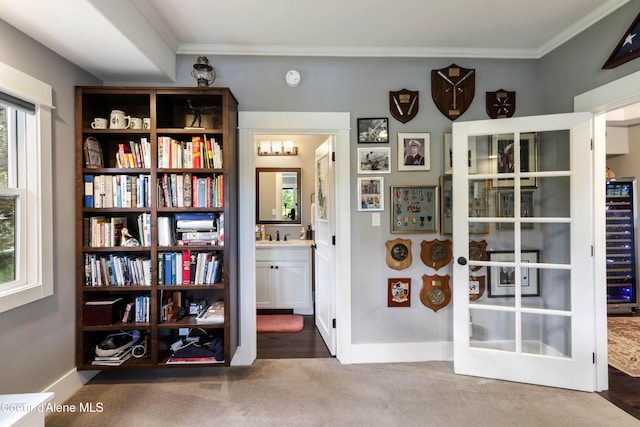 interior space with crown molding, baseboards, wine cooler, and carpet