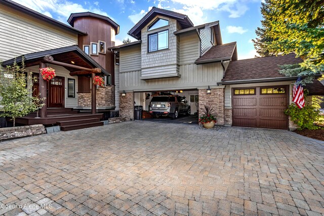craftsman house featuring a shingled roof, stone siding, decorative driveway, and an attached garage