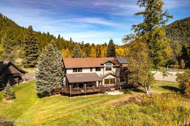 rear view of property with a deck and a lawn