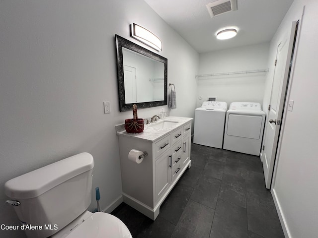 bathroom featuring vanity, washing machine and dryer, toilet, and tile patterned flooring