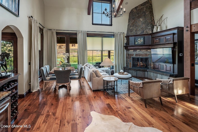 17021 S Citrine Dr, Coeur Dalene, ID 83814 - living room with arched walkways, a towering ceiling, a notable chandelier, wood finished floors, and a stone fireplace