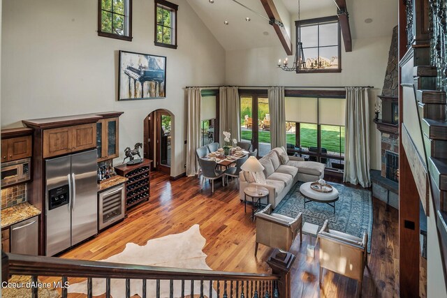 17021 S Citrine Dr, Coeur Dalene, ID 83814 - living area featuring light wood finished floors, wine cooler, arched walkways, a notable chandelier, and high vaulted ceiling