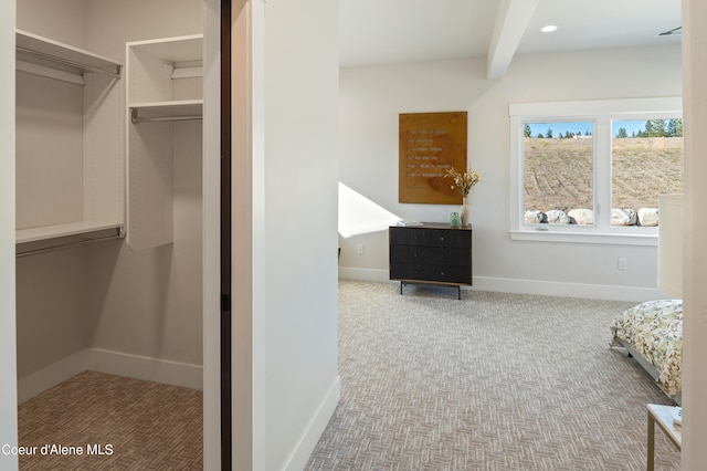 spacious closet featuring beam ceiling and carpet floors