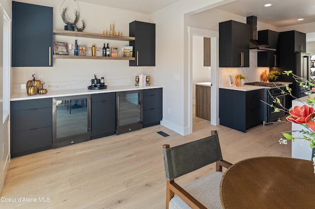 bar featuring wine cooler, range hood, gas range oven, and light wood-type flooring