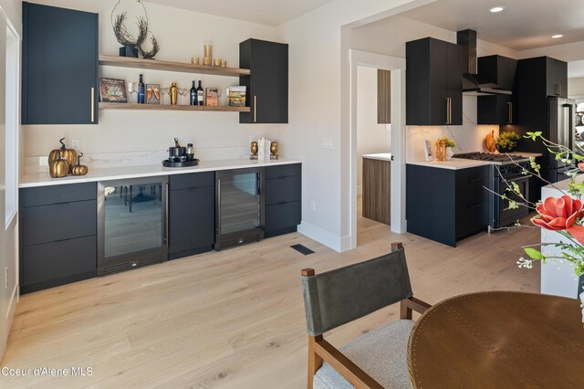 2747 W Lumber Ln, Coeur Dalene, ID 83814 - indoor wet bar featuring beverage cooler, wall chimney exhaust hood, light wood-style floors, range with gas stovetop, and recessed lighting