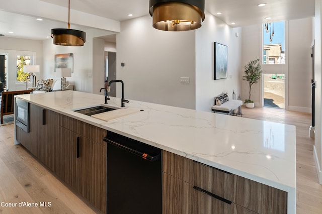 kitchen with sink, light hardwood / wood-style flooring, dishwasher, stainless steel microwave, and decorative light fixtures